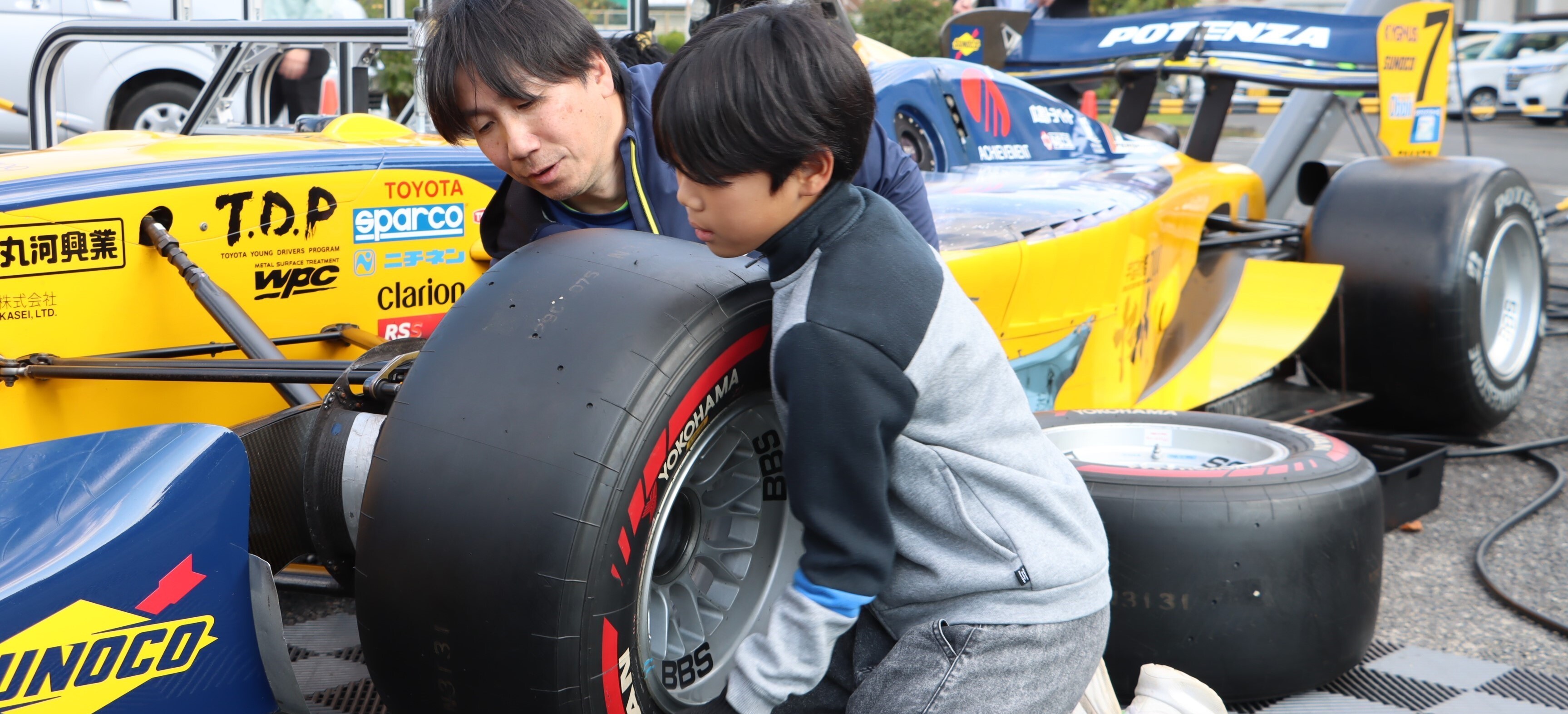 プロドライバーによる出前授業。スーパーフォーミュラのマシンのタイヤ交換を体験する児童