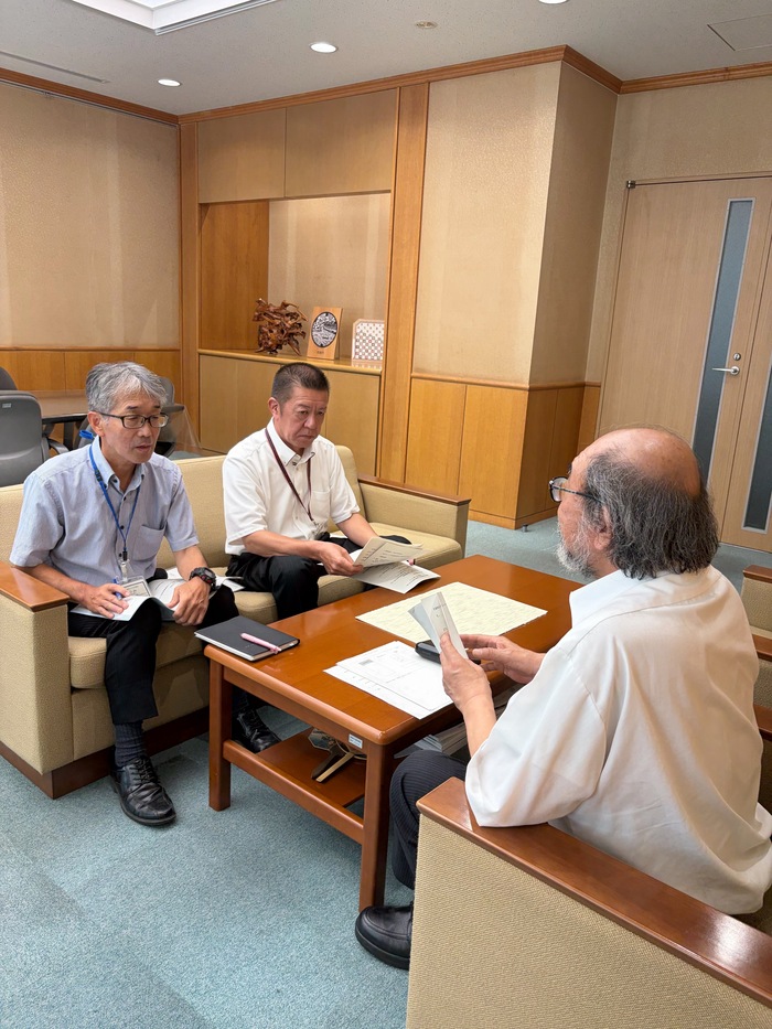 写真：会長（右手前）から上下水道事業管理者（左手前）及び上下水道局次長（左奥）へ答申の趣旨説明